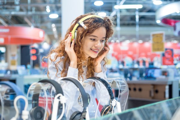 open-air headphones buying guide happy young woman trying on headphones in store